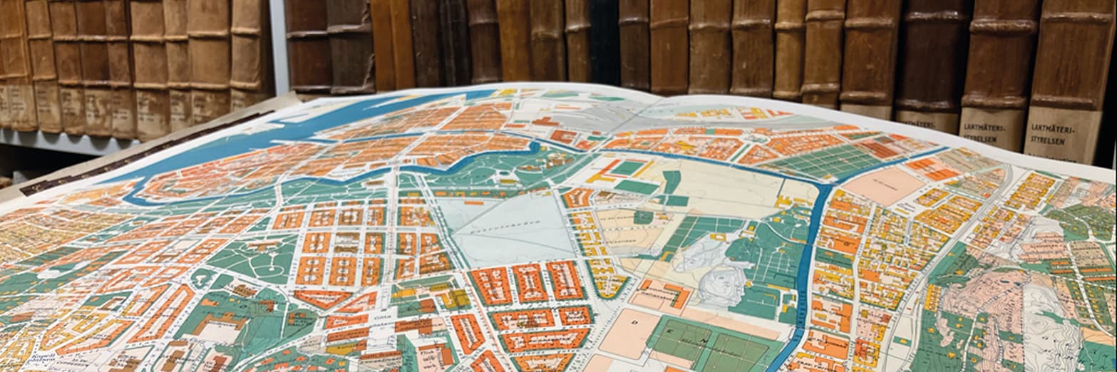 En detaljerad stadskarta som ligger på ett bord och visar olika stadsdelar, gator och landmärken, med färgglada representationer av byggnader och grönområden.