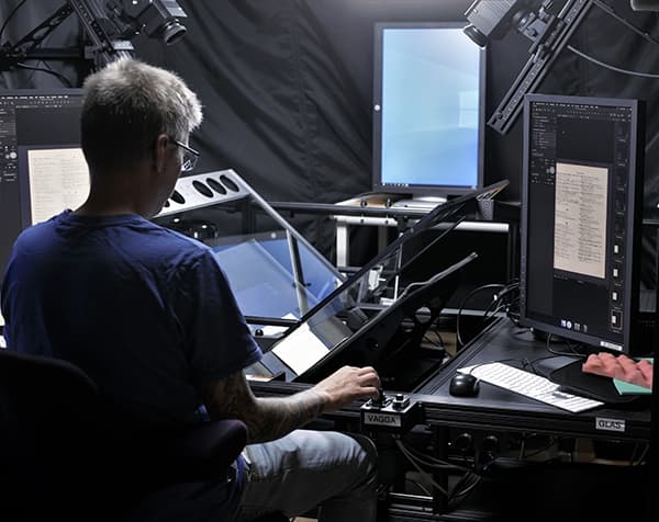 En man sitter vid en bokskanner och arbetar.