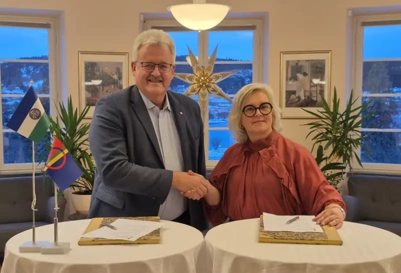 Två personer skakar hand och ler mot kameran.